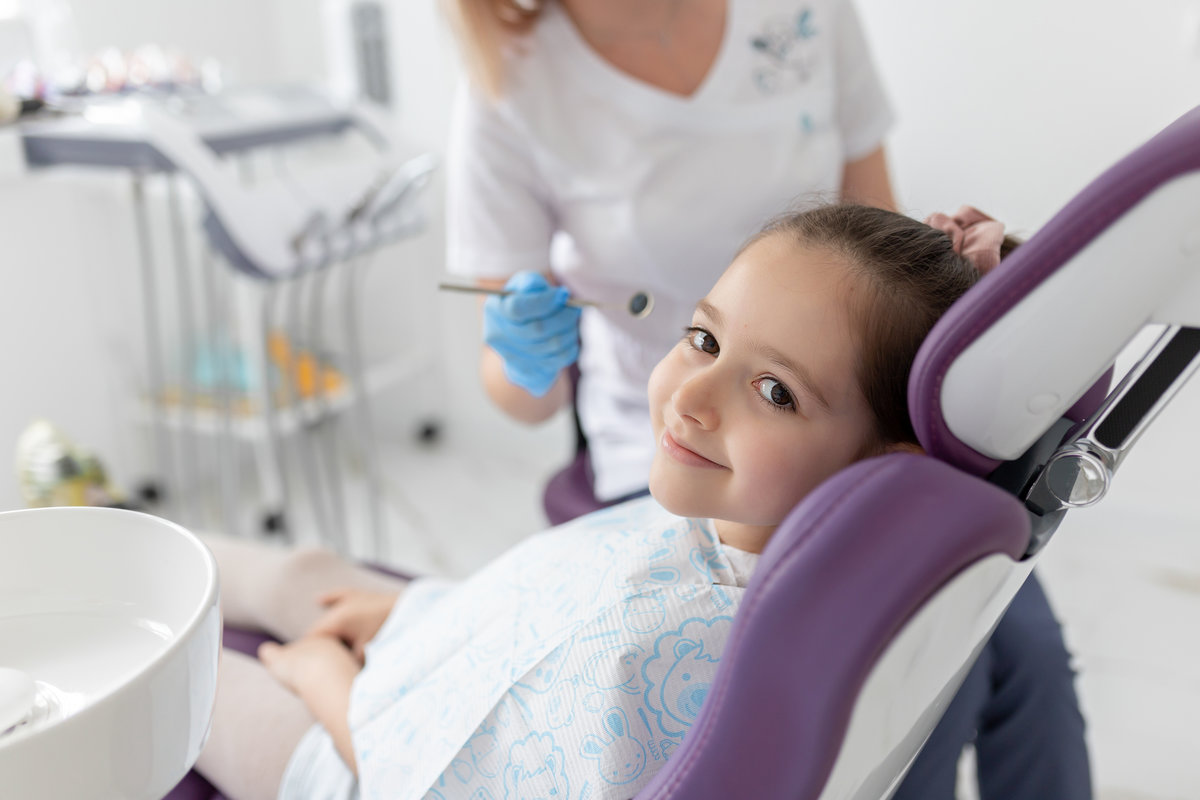 Little beautiful girl at the dentist looking at the camera and smiling